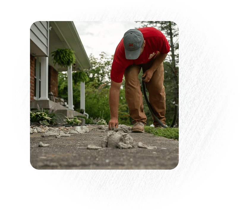 Man bending over concrete walkway to adjust concrete leveling slurry