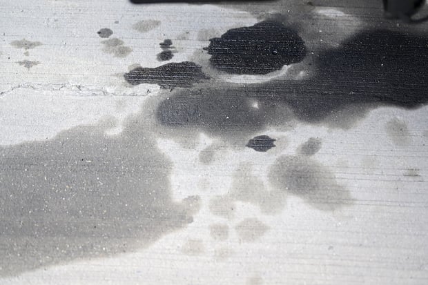Large, dark oil stains on concrete driveway