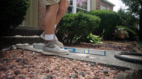 Concrete repair technician using a level to check concrete leveling repair