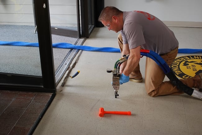 Man injecting foam beneath slab to lift concrete floor