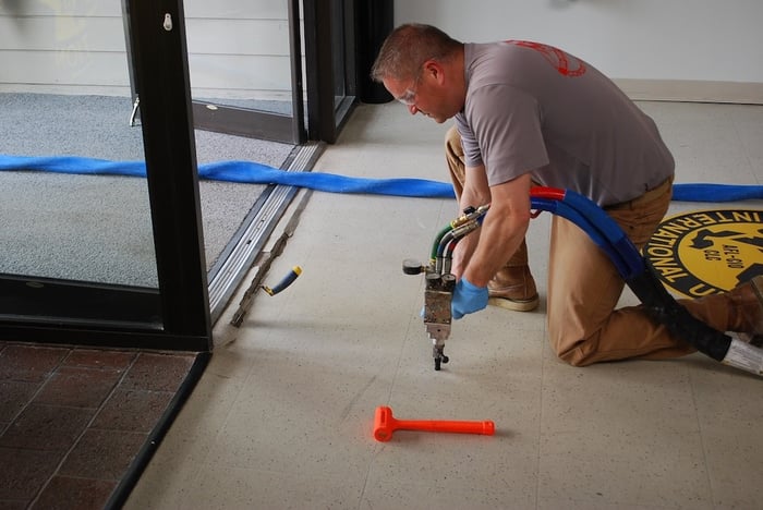 Man injecting foam beneath slab to lift concrete floor