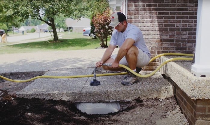 Man pumping stone slurry grout under settled walkway