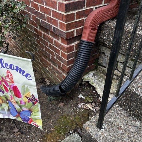 Broken downspout extension causing soil washout under concrete porch