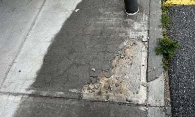 Spalling concrete covered with an overlay that is chipping away